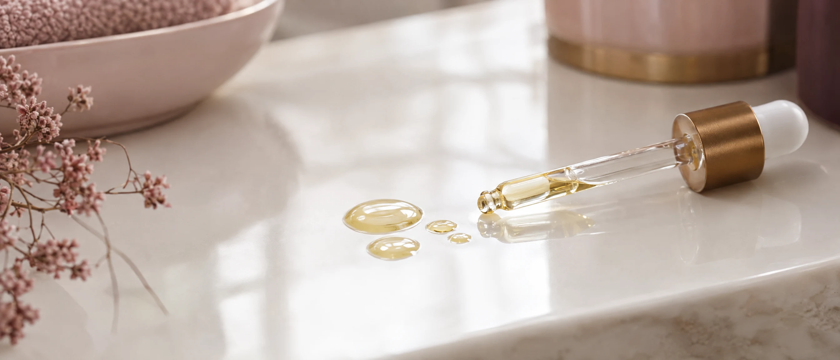 Tropfen von goldenem Fußpflegeöl auf weißem Porzellan