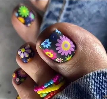 Zehennägel mit bunten Blumen auf dunklem Grund